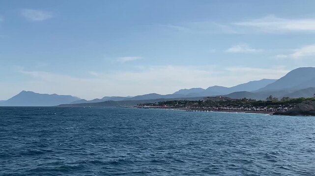 View of the Taurus mountain range. The Mediterranean Sea in Camyuva, Kemer, Turkey. View from a ship in the open sea. Seascape. Blue water. Kiris district.