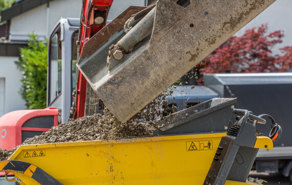 Close-up of excavator at construction site, in use filling a mini dumper