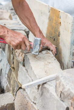 Building a brick wall of natural stone, with hammer, handmade, close-up of human hands