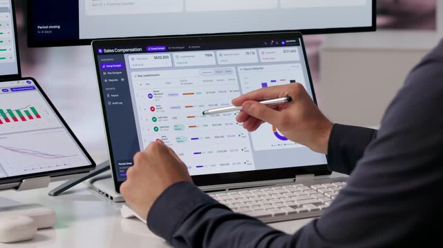 Sales Manager Reviews Commission Dashboard On Dual Laptop Screens