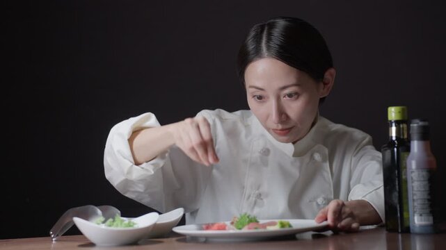 料理の盛り付けをする女性シェフ