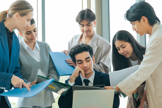 Corporate manager looking exhausted while reviewing reports from multiple colleagues during a project meeting. Office overload, business pressure, teamwork and decision making under tight deadlines.
