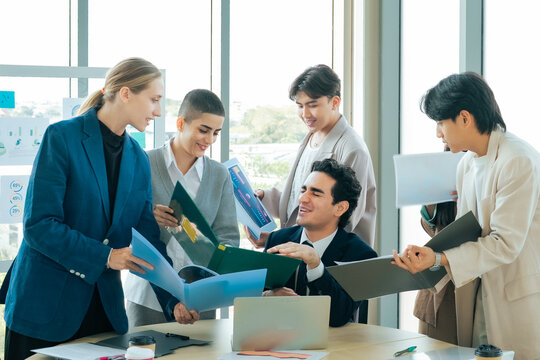 Business manager overwhelmed multiple project requests colleagues present reports documents during busy office meeting. Workplace pressure, deadline stress and heavy workload corporate environment.