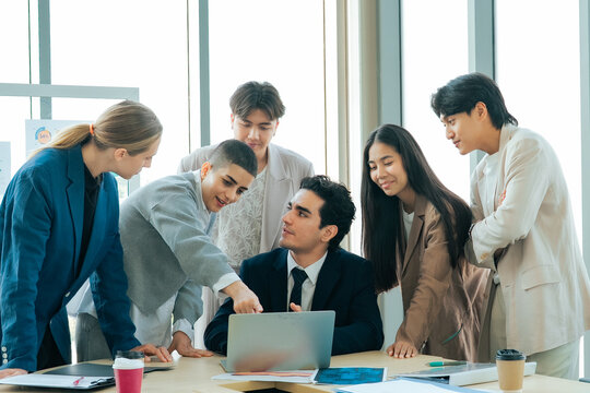 Business team working together around a laptop while sharing ideas and reviewing documents. Collaborative problem solving, leadership and teamwork create effective business solutions.