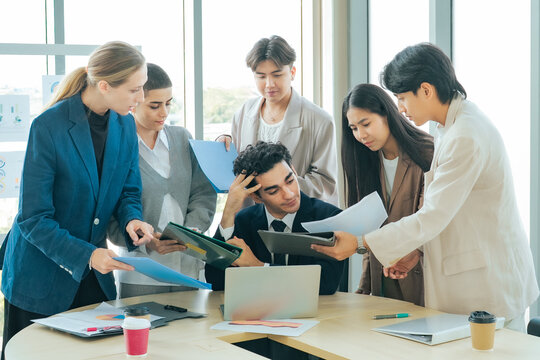 Overworked manager reviewing reports while colleagues wait for decisions during a business meeting. Corporate stress, deadline pressure, teamwork challenges and project management office.