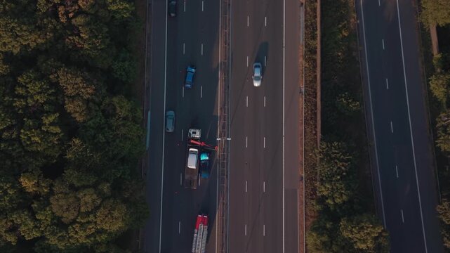 Drone top-down aerial view of a recovery truck loading a damaged vehicle after a road traffic accident on the M6 motorway near Birmingham, with emergency services, temporary lane closure and traffic