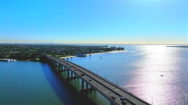 Drone revealing a constant flow of traffic driving across a bridge towards Sydney, Australia