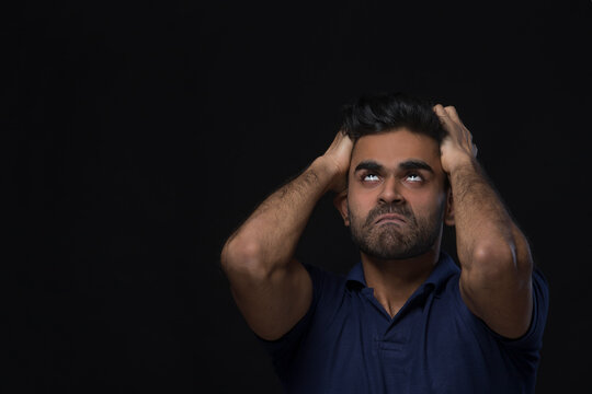 closeup of an angry man holding his head