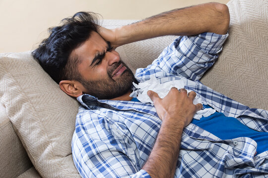 Man in pain on the sofa with tissues 