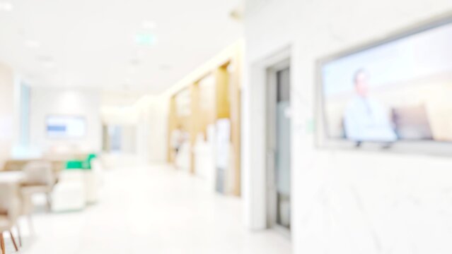 Blur abstract background of corridor in clean hospital. Blurry view of aisle in office with light floor. Defocus walkway in white light building hall with patient registration at reception desk.