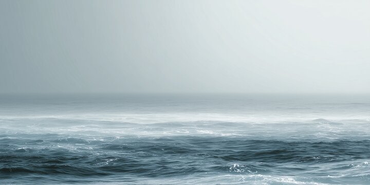 Calm mist ocean waves under a hazy overcast  horizon grey sky in soft blue monochromatic sea waters, minimal seascape
