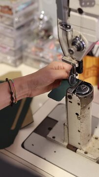 Artisan hands stitching green leather on an industrial sewing machine