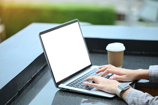 Unrecognizable young businesswoman using laptop at on office terrace.