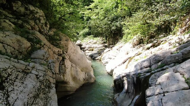 White Rock Canyon, Khosta River winding between steep white limestone cliffs and lush green forest in Sochi, Russia.