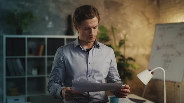 Young man financial analyst checking business reports in office, doing paperwork