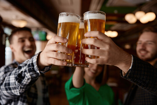 Group of colleagues enthusiastically clinking beer glasses in a pub