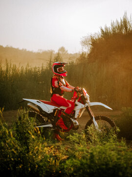 Motocross rider wearing gear on a dirt bike during a sunny golden hour session in the countryside