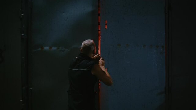 Male hacker walking into a hidden computer lab inside a dark, futuristic container at night