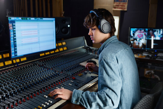 Sound engineer carefully calibrating sound levels in dimly lit studio