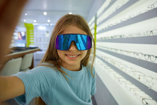 Cheerful girl wearing sunglasses capturing mirror selfie photograph