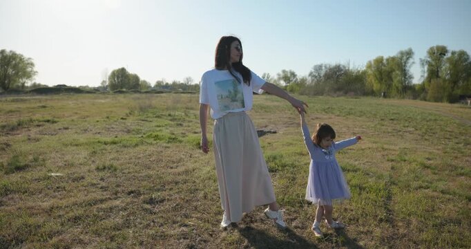 Young mother with child daughter spend time playing enjoying nature. 4K 10-bit