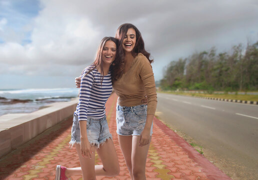Two women walking on a promenade by sea