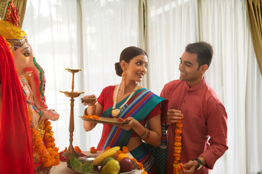 Husband and wife decorating for the ganesh chaturthi pooja
