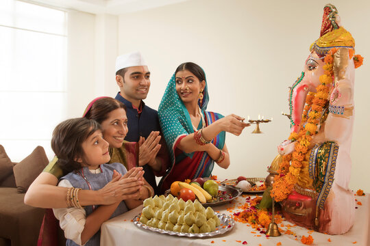 Family praying on Ganesh Chaturthi where grandma teaches grandson how to pray.
