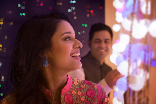 Husband and wife decorating the house with lights on the occasion of diwali