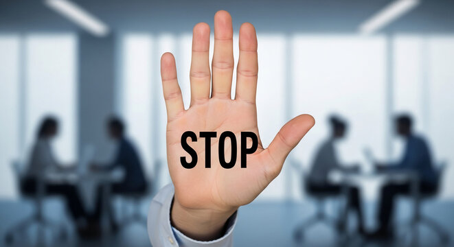 Hand displaying the word "STOP" in a blurred office setting, representing a halt or prohibition in business context