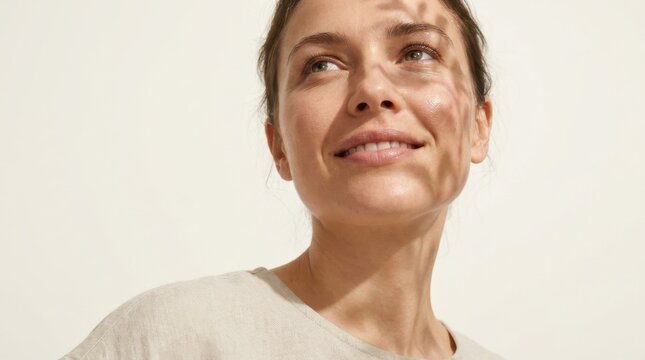 Natural Beauty Portrait of Young Woman with Soft Leaf Shadow Patterns on Her Face and Shoulders Against a Minimalist Light Cream Background