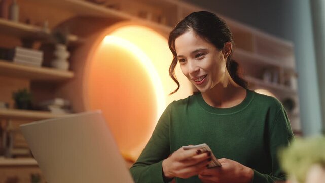 Happy Korean woman counting cash in front of laptop, successful online business