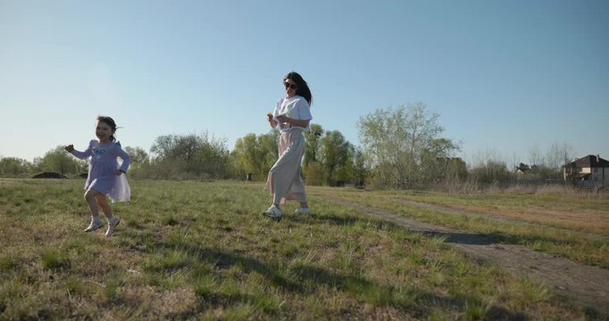 Young mother with child daughter spend time playing enjoying nature. 4K 10-bit