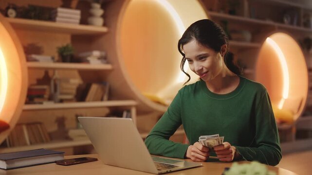 Young Asian woman counting money after successful online freelance project