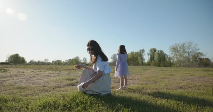 Young mother with child daughter spend time playing enjoying nature. 4K 10-bit