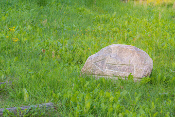 Granite stone in a green meadow. Natural rock sitting in a lush grassy field. © Indre