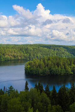 A scenic high-angle view of Lake Aulanko (Aulangonj&auml;rvi) surrounded by dense green pine and spruce forests under a blue cloudy sky in H&auml;meenlinna, Finland. Beautiful Scandinavian summer landscape
