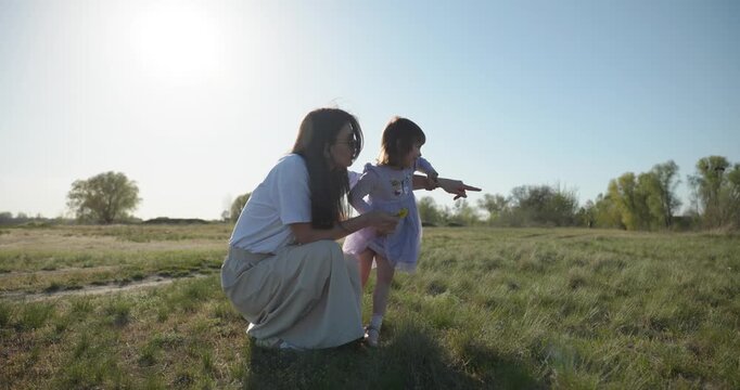 Young mother with child daughter spend time playing enjoying nature. 4K 10-bit