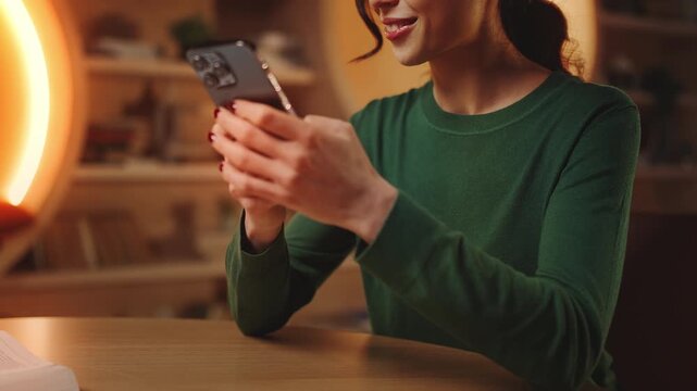 Cheerful young woman texting on cellphone instead of studying, procrastination