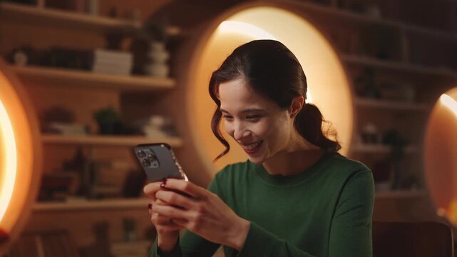 Happy young Asian woman scrolling through social media app on phone in library