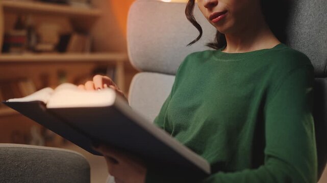 Focused female student flipping through book pages in library, reading hobby