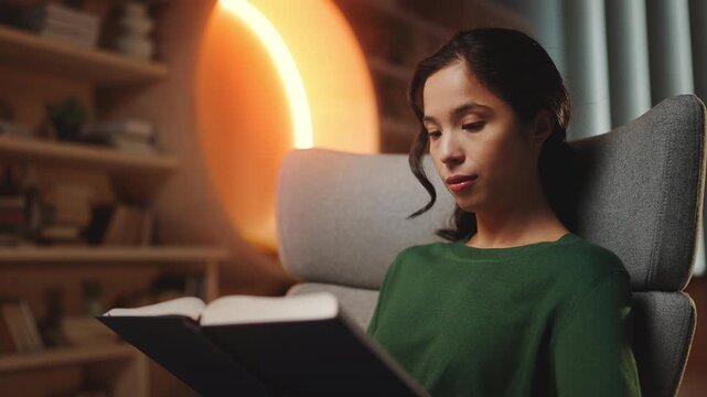 Focused Asian female reading interesting book in modern library, hobby time