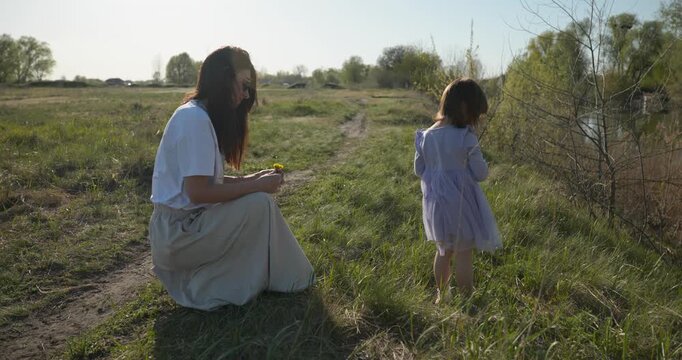 Young mother with child daughter spend time playing enjoying nature. 4K 10-bit