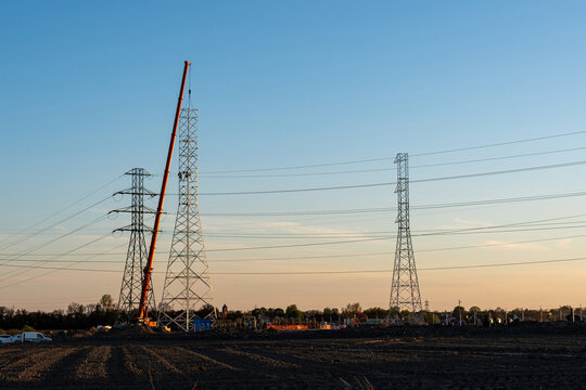 Crane Erecting Steel Transmission Tower Near Power Lines