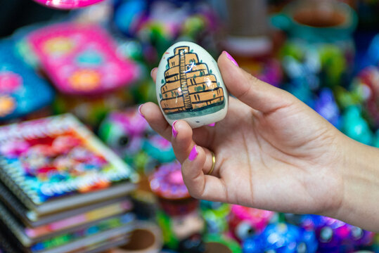 Hand Holding Hand Painted Stone Souvenir Featuring Ancient Pyramid Design in Mexican Artisan Market
