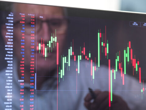 Reflection of a stock trader viewing the performance of a company share price on screen