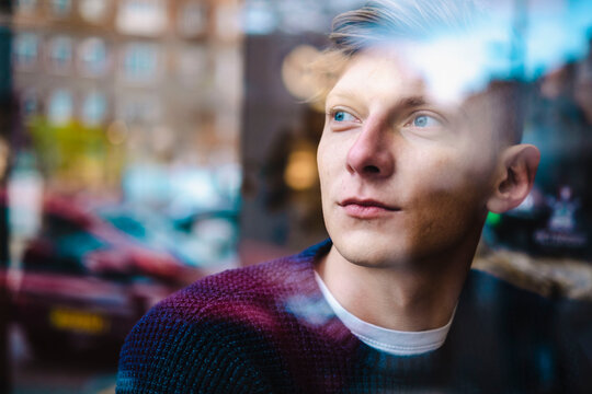 Contemplative young man seen through glass window