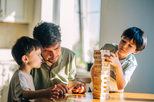 Dad and sons playing wooden block game at home