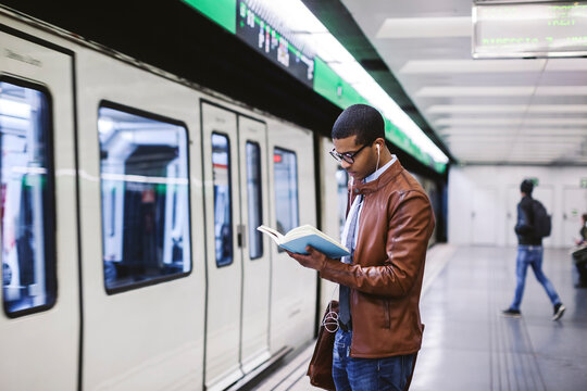 Spain, Barcelona, businessman standing at underground station platform reading book