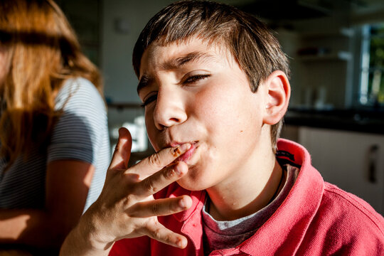Portrait of boy at home licking his finger